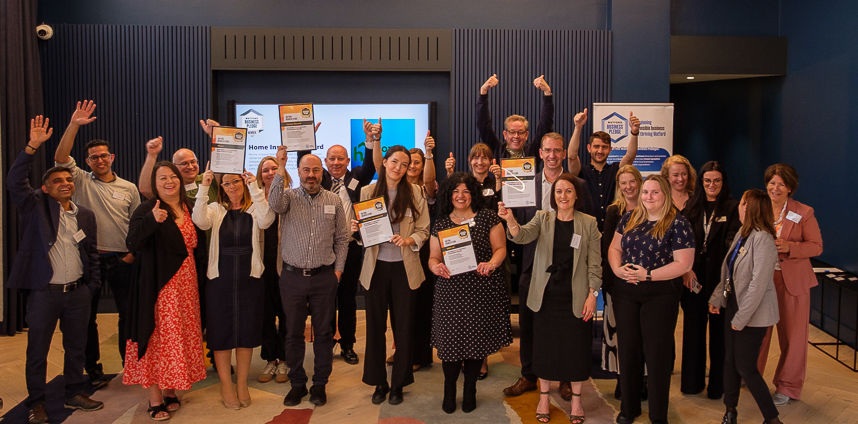 Large group of diverse people cheering, holding certificates, celebrating success.