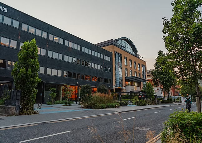 Modern office building complex with dark and brick sections by a street.