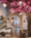 Elegant restaurant interior features pink cherry blossoms, tables, and cozy lanterns.