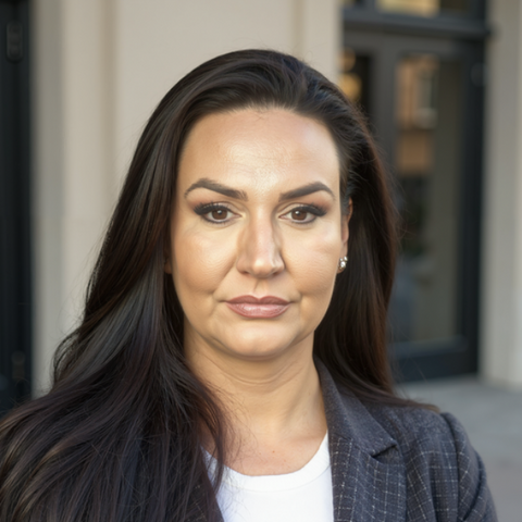 Professional woman with long dark hair, wearing a white shirt and blazer.