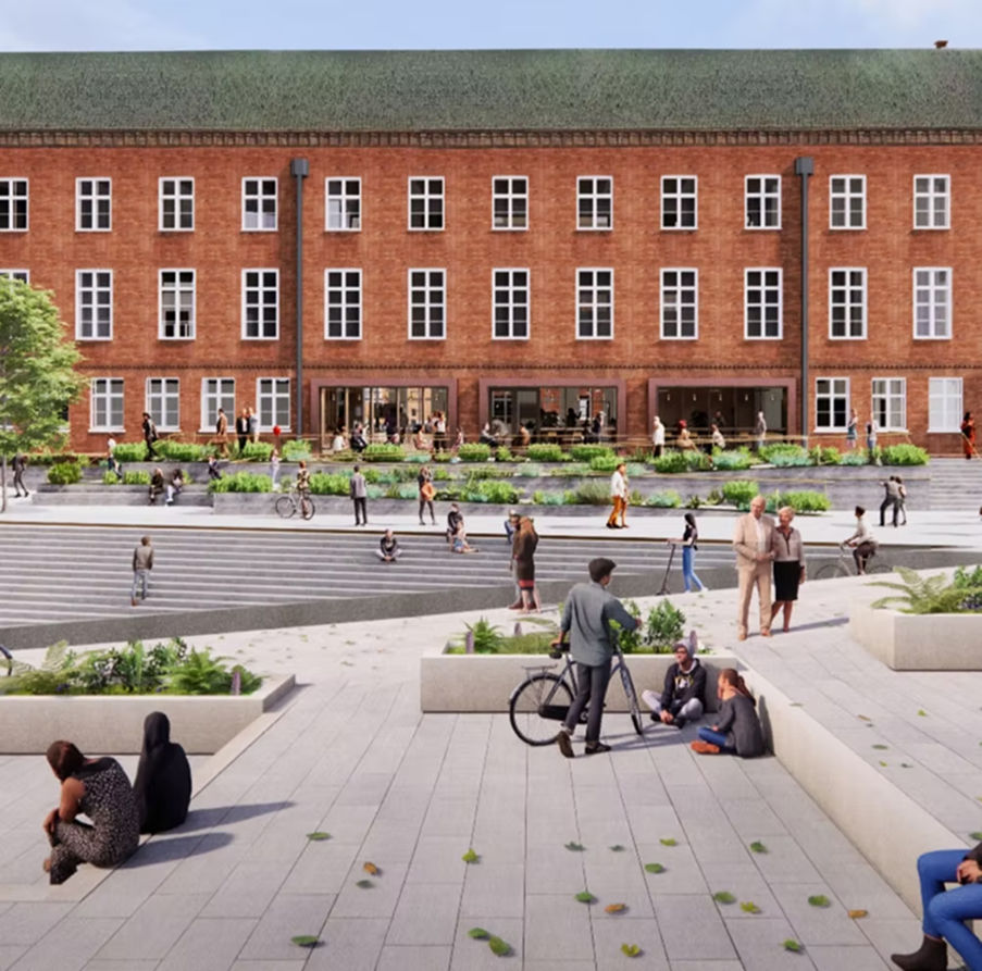 People gathering in a modern public square before a red brick building.