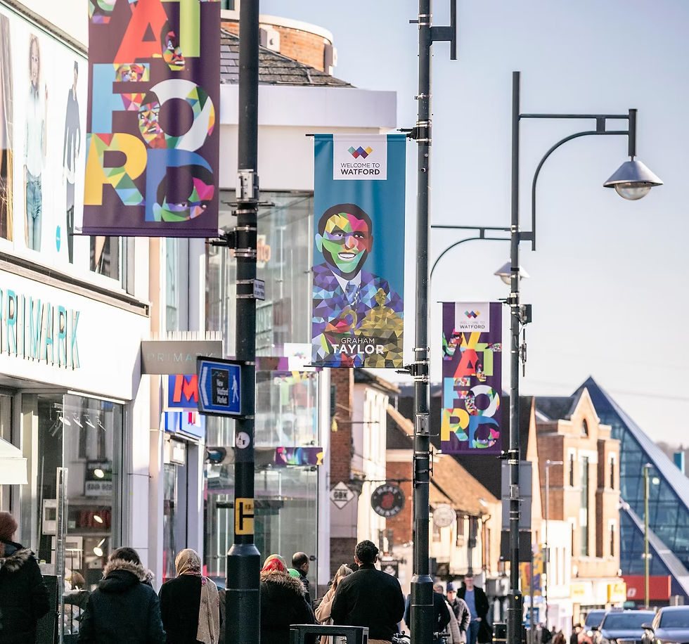 People walk past 'Primark', street decorated with 'AFRO', 'AFRICAN HISTORY MONTH' banners.