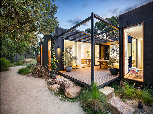 Modern modular home with open deck and lush landscaping.