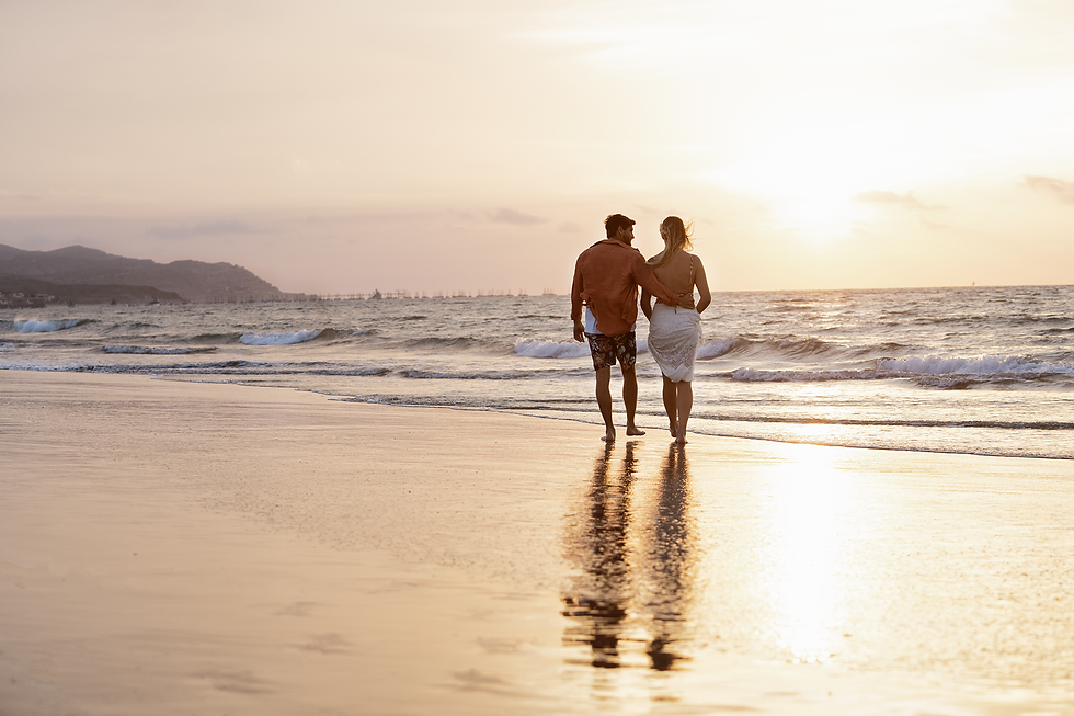 Pareja caminando por la playa frente al mar al atardecer en Norte Suites Boutique.
