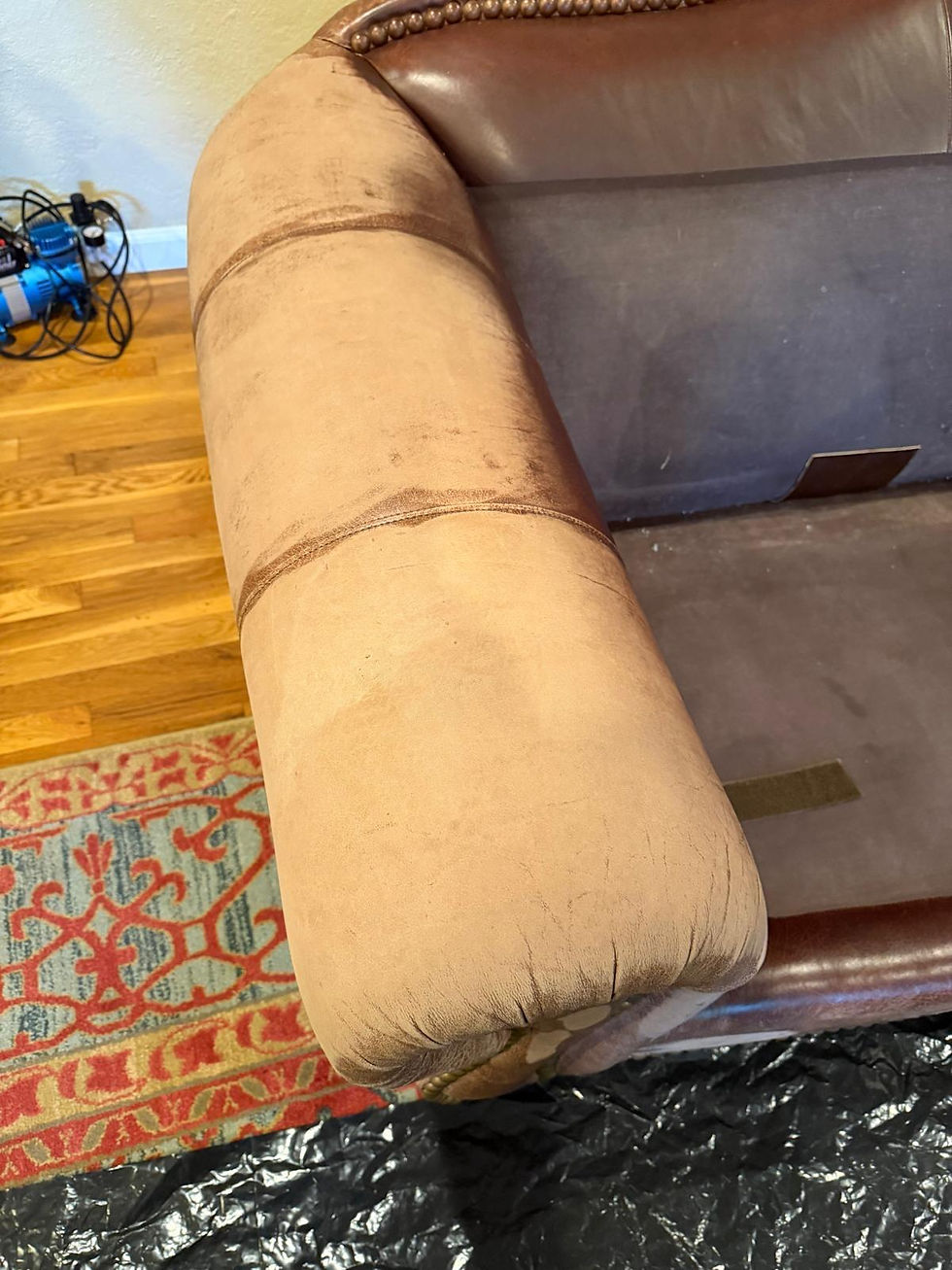 Close-up of a heavily worn leather sofa armrest before restoration in San Jose, CA showing severe color loss, faded leather, body oil buildup, worn finish, and surface damage on a 25-year-old brown leather sofa before professional leather repair, custom color restoration, refinishing, refurbishing, and reconditioning by All Leather Works.