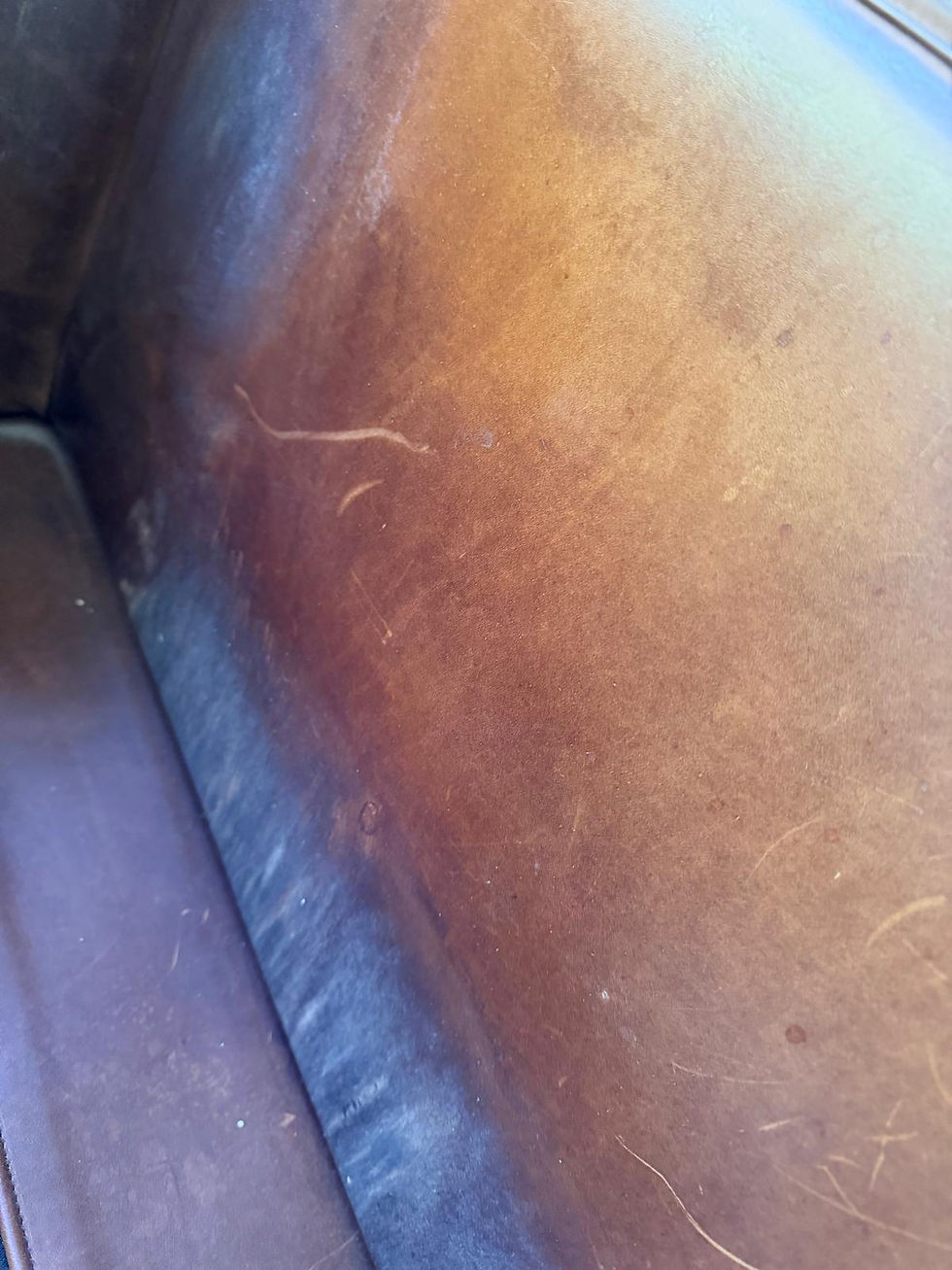Close-up before photo of worn leather showing scratches, body oil damage, color fading, and finish deterioration before professional leather repair, leather color restoration, leather refinishing, and leather reconditioning in San Leandro, CA by All Leather Works LLC.