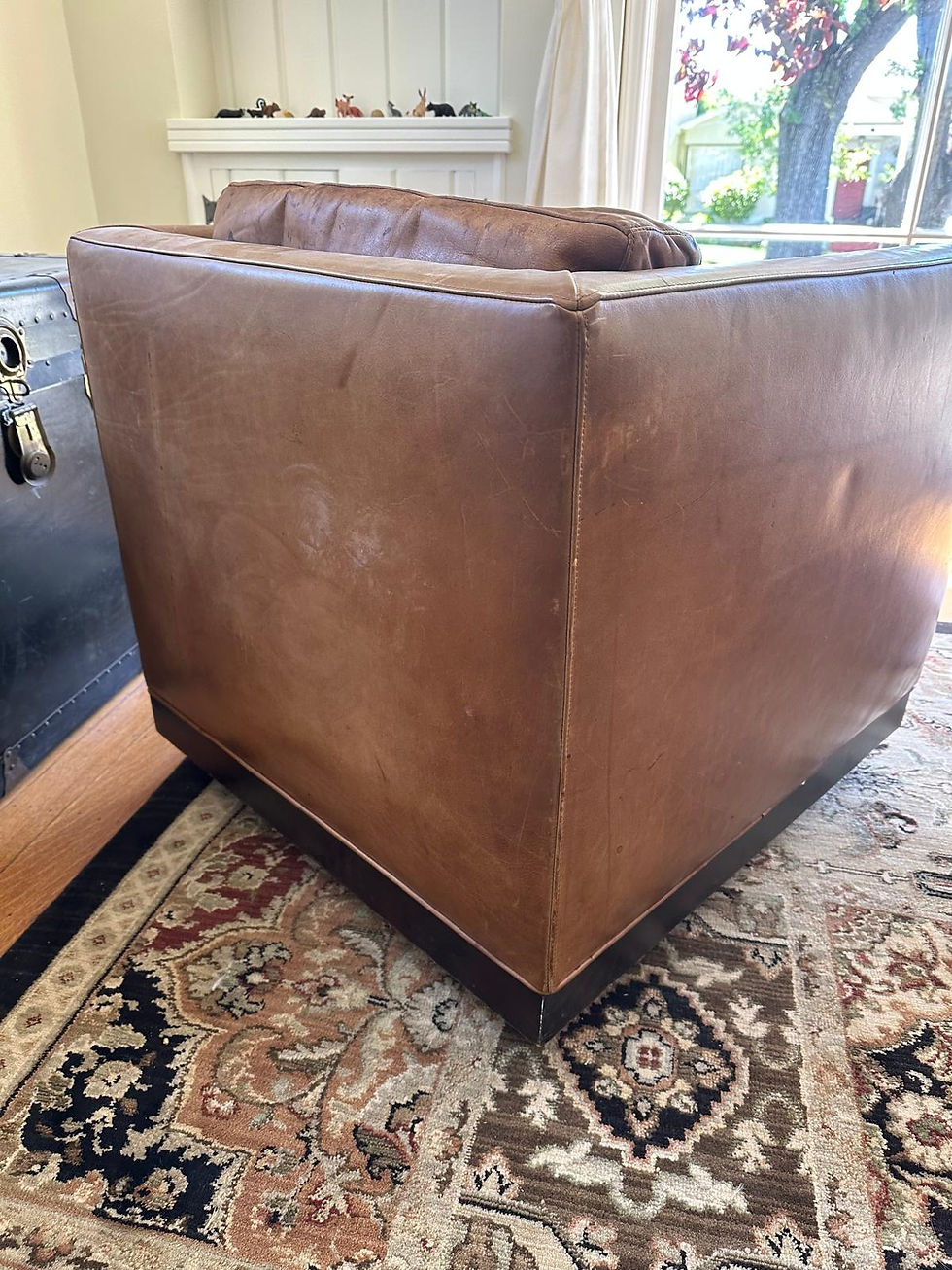 Back view of a leather club chair before restoration in San Leandro, CA showing faded leather, surface wear, scratches, and color loss before professional leather cleaning, leather color restoration, leather refinishing, and leather reconditioning by All Leather Works LLC.