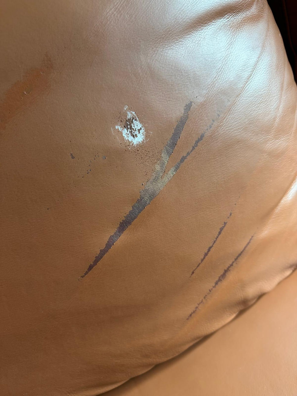 Close-up of deep scratches, finish damage, and color loss on a brown leather manual reclining loveseat requiring professional leather scratch repair, color restoration, and leather refinishing in San Francisco, California.