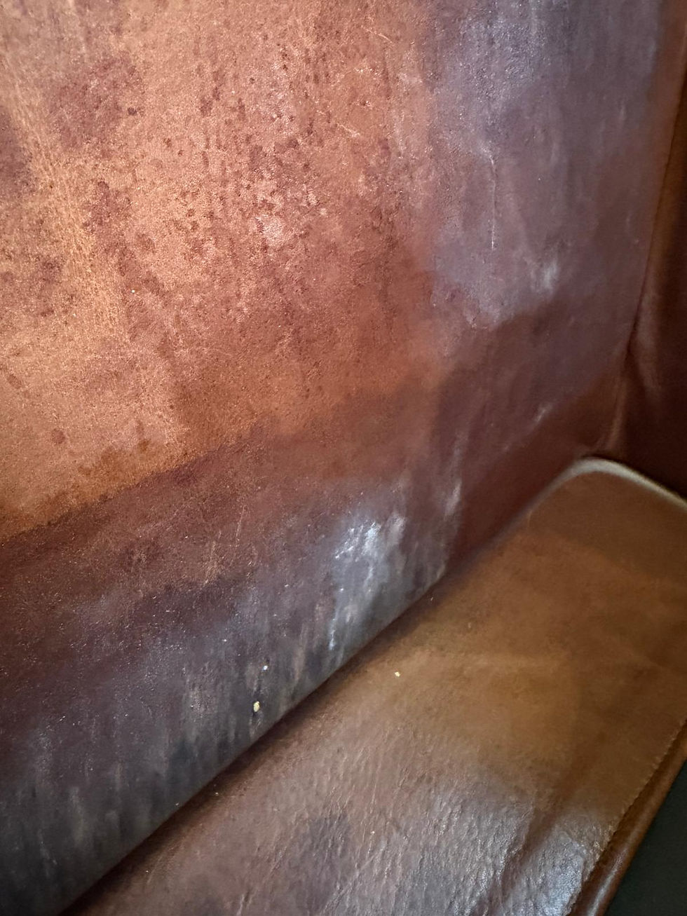 Close-up before photo of heavy body oil damage, leather finish deterioration, color loss, and worn leather on a club chair in San Leandro, CA before professional leather repair, leather color restoration, leather refinishing, and leather reconditioning by All Leather Works LLC.