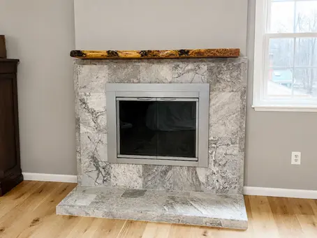 New fireplace with stainless doors, marble tile surround and live-edge wood mantel in Alexandria VA — Vale Construction