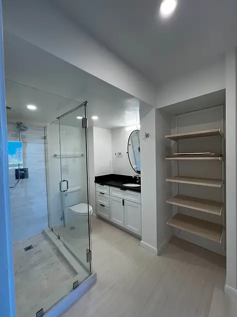 Renovated condo kitchen with white shaker cabinets, light marble-look counters, white subway tile backsplash, undercabinet lighting and black appliances