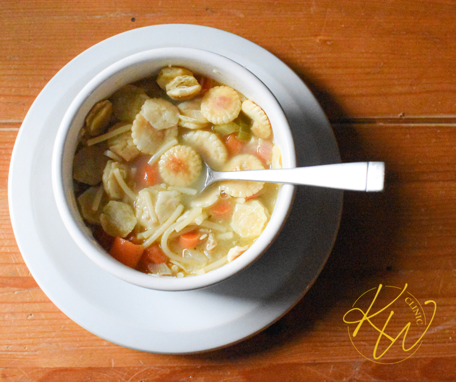 a white bowl of soup with crackers and a spoon