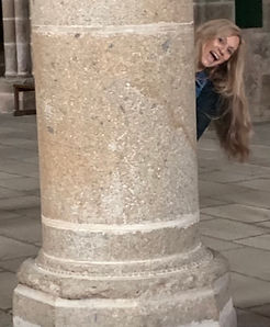 Girl peeking out from a wide column at Mont-St. Michel, France