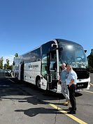 White and black tour bus with tour guide and driver standing in front in Orvieto, Italy