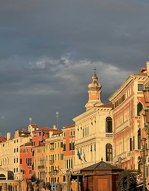Gray cloudy sky over old sunlit pastel colored buildings in Venice, Italy
