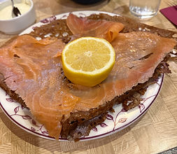 Crispy crepe topped with smoked salmon and a cut lemon at Montparnasse's Creperie Le Petit Josselin in Paris, France