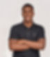 Promise, stands with his arms crossed. He's wearing a dark gray textured polo shirt, photographed against a white background.