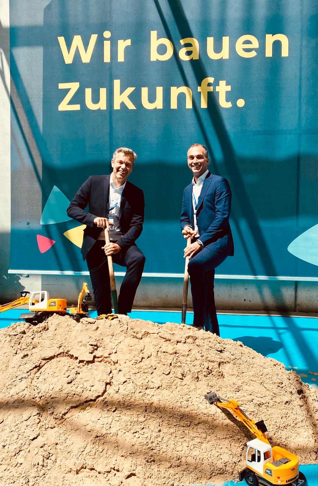 Two visitors with spades in front of the words “We are building the future” at Real Estate Arena.