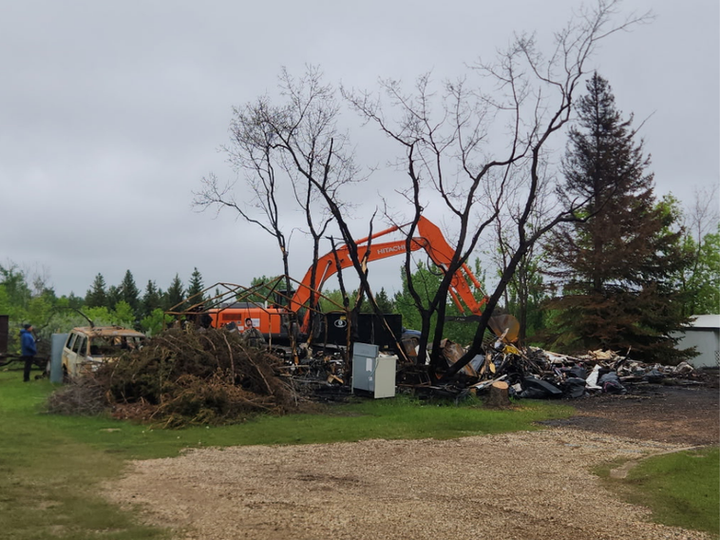 Excavator cleaning up a burned structure in Central Alberta