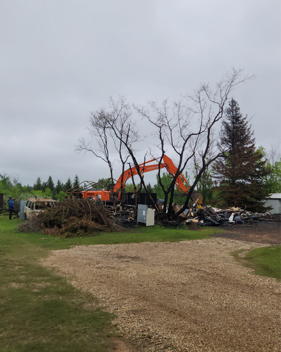 Excavator cleaning up a burned structure in Central Alberta