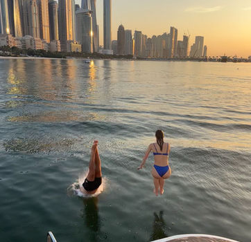 Zwemmen in Dubai tijdens zondergang boot tour tijdens groepsreis in Dubai