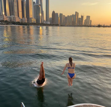 Zwemmen in Dubai tijdens zondergang boot tour tijdens groepsreis in Dubai