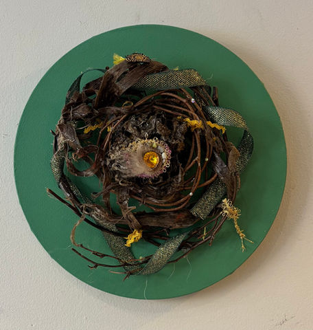 a mandala with a hornet's nest centre surrounded by twigs and ribbon
