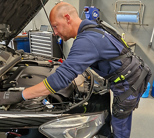 Mechanic with BionicBack exoskeleton works in a bent position on an engine and reduces the strain on the lower back.