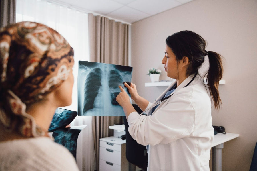 A primary health care provider looks at an x-ray with a patient.