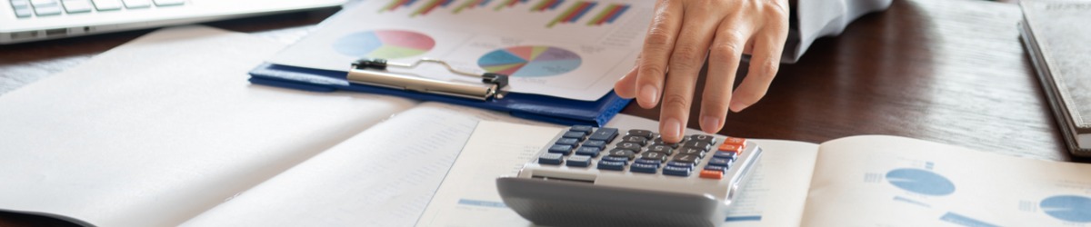 person with calculator and charts on clipboard