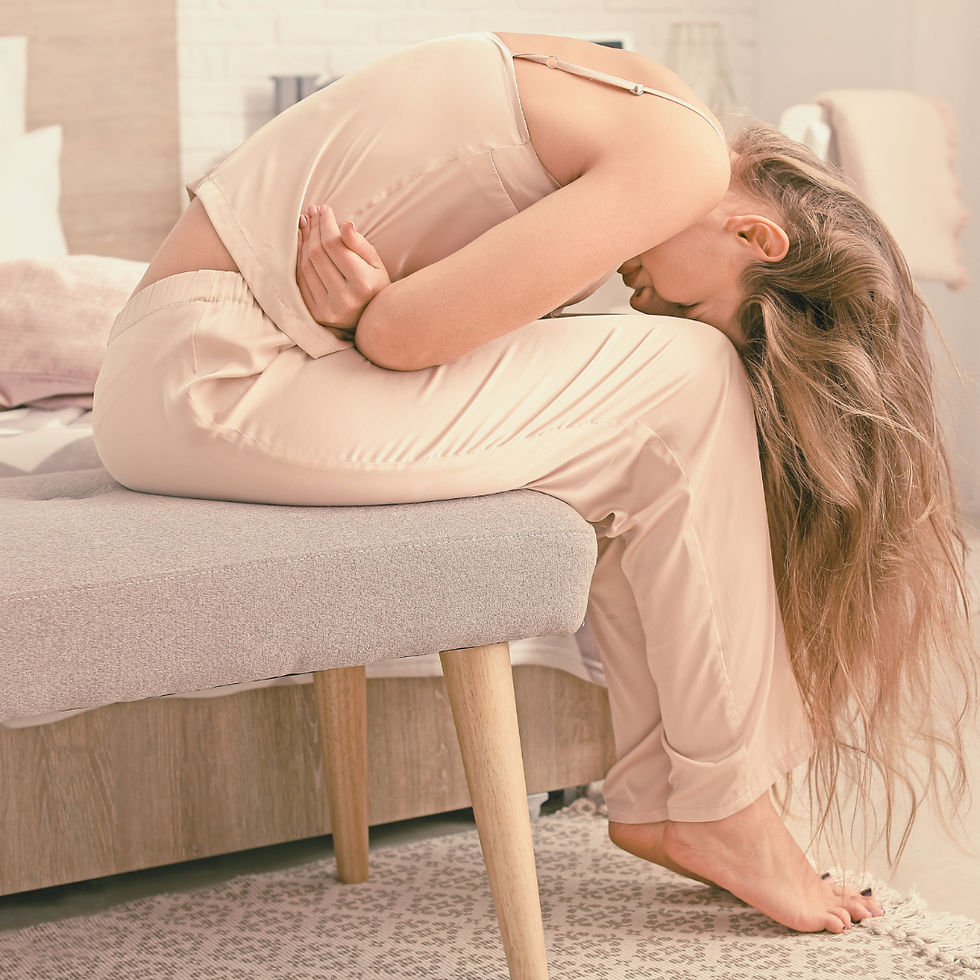 Femme assise sur le bord d’un lit, recroquevillée en position fœtale, tenant son ventre avec les mains, visiblement en proie à une douleur pelvienne intense. La scène évoque les douleurs menstruelles ou liées à l’endométriose, dans un environnement doux et intime.