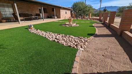 Artificial turf backyard with stone details and fountain