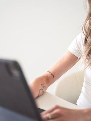 Queer website designer for therapists' arms with a pronoia tattoo typing on her ipad in Vancouver BC.