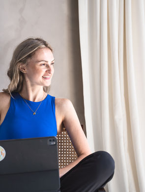 Blonde female website designer for therapists in BC wearing a blue tank smiling looking sideways.