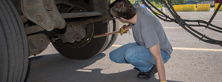 18-Wheeler Pre-trip Tire Inspection - A professional driver is using a tire thumper to che