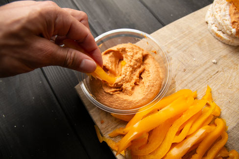 Dipping a slice of yellow bell pepper into hummus.
