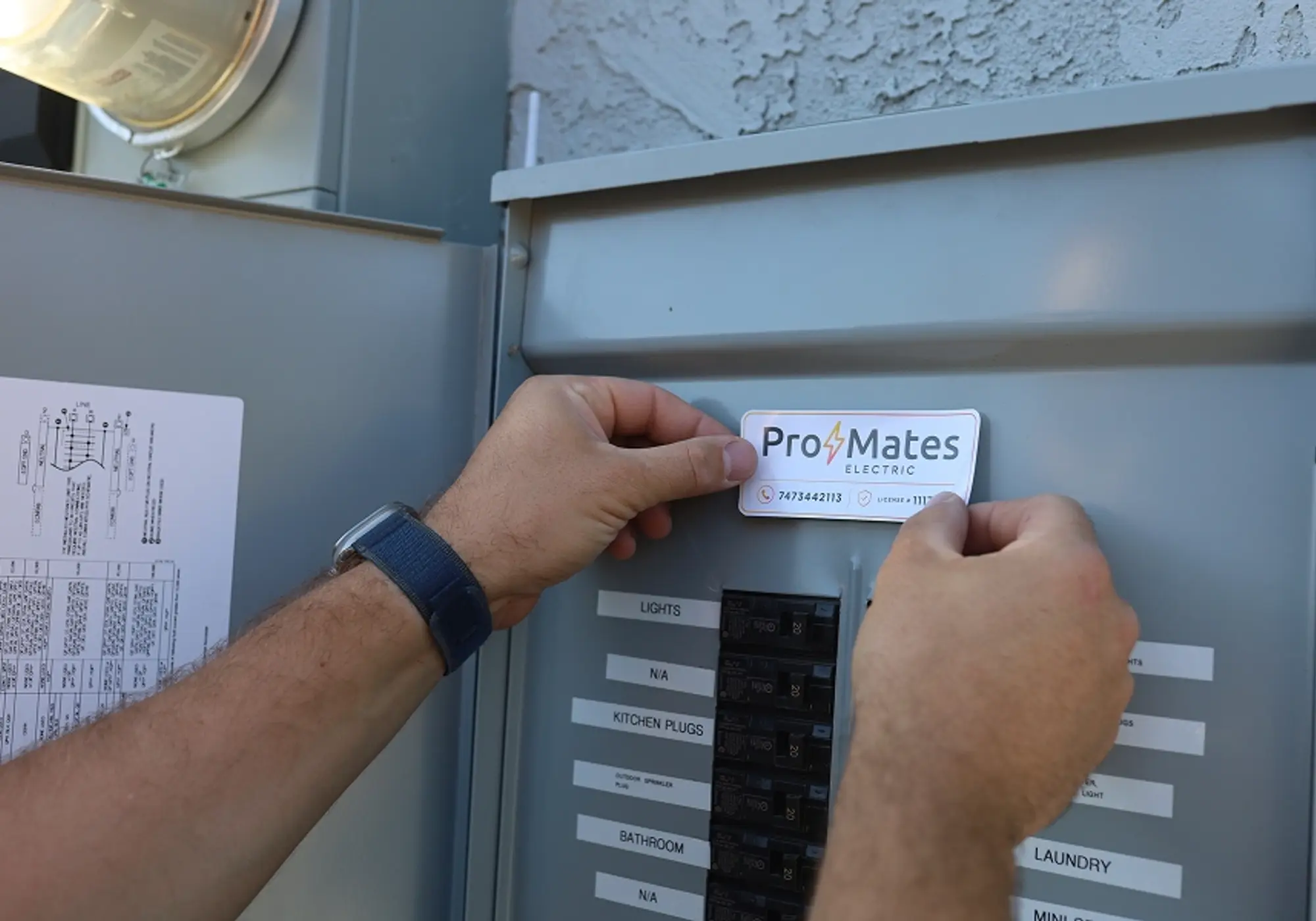 ProMates Electric technician applying a service label inside a residential electrical panel