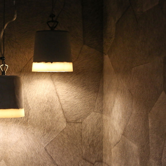 Suspensions lumineuses dans un restaurant en Savoie révélant un revêtement mural texturé effet peau dans un intérieur chaleureux et contemporain