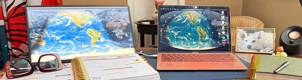 Desktop showing a laptop, second monitor, day planner, notebook, and other office supplies and personal items.