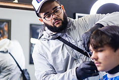 Guy in hat cutting hair
