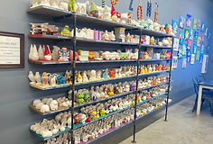 A row of ceramic sculptures, including mugs, some painting and some unpainted.