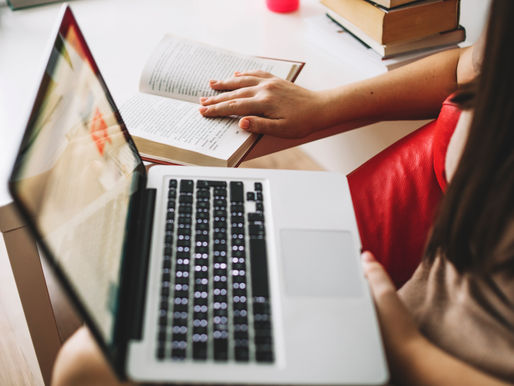 Business professional multitasking with a laptop and an open book, symbolizing how content works around the clock to inform and influence buyers.