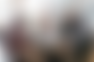 Sales and marketing team collaborating around a table, reviewing documents and discussing strategy in a modern office, representing lead nurturing and guiding prospects through the sales funnel.