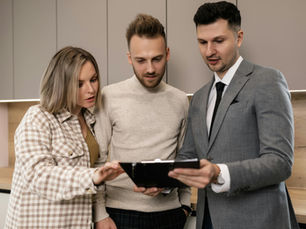 Couple reviews paperwork with a realtor in a modern home. Real estate purchase.