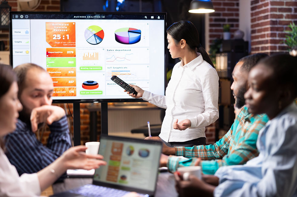 Sales professional presenting business analytics on a screen to a team during a meeting, demonstrating confidence and clear communication in a sales presentation.