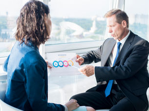 Business professional explaining an infographic to a colleague during a meeting, symbolizing collaboration and strategic communication in sales enablement.