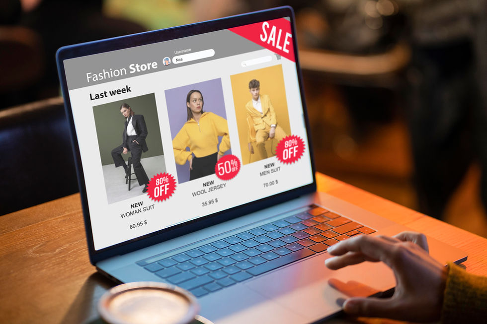 A person browsing an ecommerce website design on a laptop, featuring a fashion store with discounted clothing items and a "SALE" banner, in a cozy café setting.