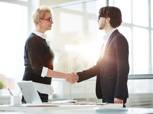 Business professionals in formal attire shaking hands in office