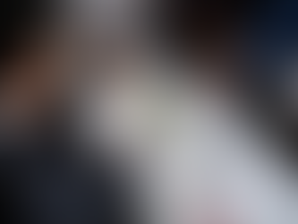 A group of business professionals gathered around a table during a meeting, analyzing financial charts and graphs displayed on a tablet. Documents, calculators, and notes are spread across the table as they discuss data and strategies.