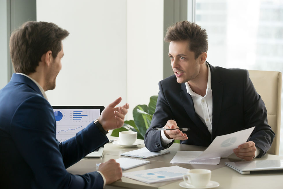 Two businessmen in suits discuss a business proposal at a table, reviewing charts, documents, and financial reports during a meeting.